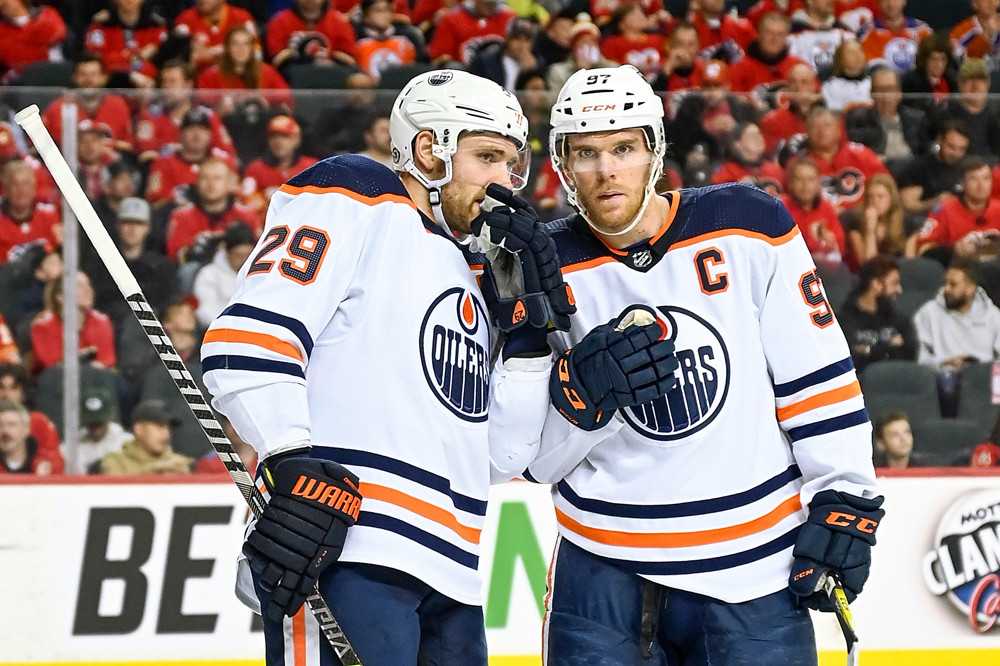 Improving defence a priority for Edmonton Oilers 42 Edmonton Oilers forwards Leon Draisaitl and Connor McDavid stand on ice in white jerseys talking before taking a face-off.