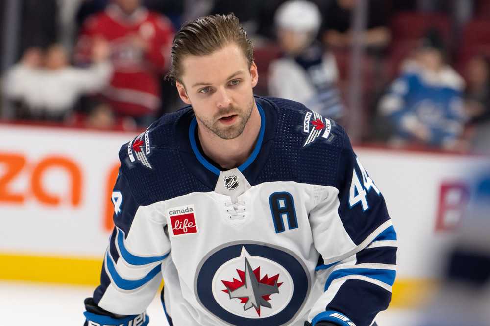 Winnipeg Jets defenceman Josh Morrissey wearing the team's white and blue away jerseys is skating in warmups without a helmet on