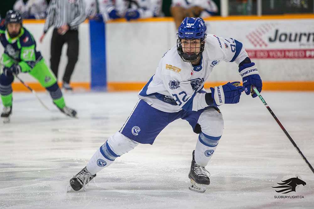 Cubs' defenceman Josh Kavanagh wearing the team's white jersey hustles for the puck against the Espanola Paper Kings on Thursday, January 4th