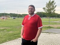 Coach Tim Marsh poses with a red jersey on