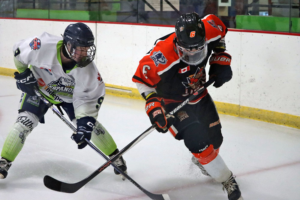 Two NOJHL players battle for the puck in a game between the Espanola Paper Kings and Hearst Lumberjacks